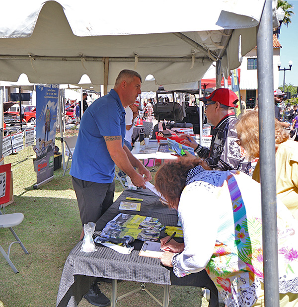 Solivita annual car show sales rep Carlos speaking with potential clients at the MD Construction tent. MD construction sponsoring this annual car show as a red corporate sponsor choice