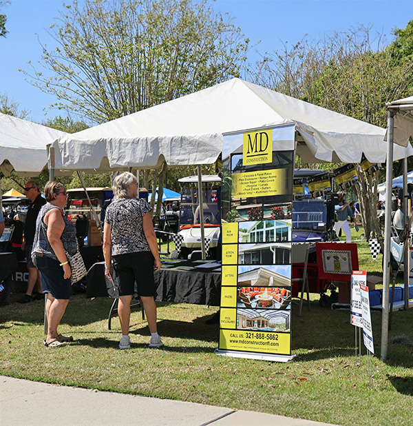Solivita annual car show sales rep Carlos speaking with potential clients at the MD Construction tent. MD construction sponsoring this annual car show as a red corporate sponsor choice