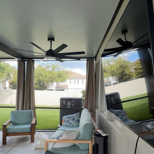 Patio furniture, fan, and tv setup in a screen room in Winter Garden.